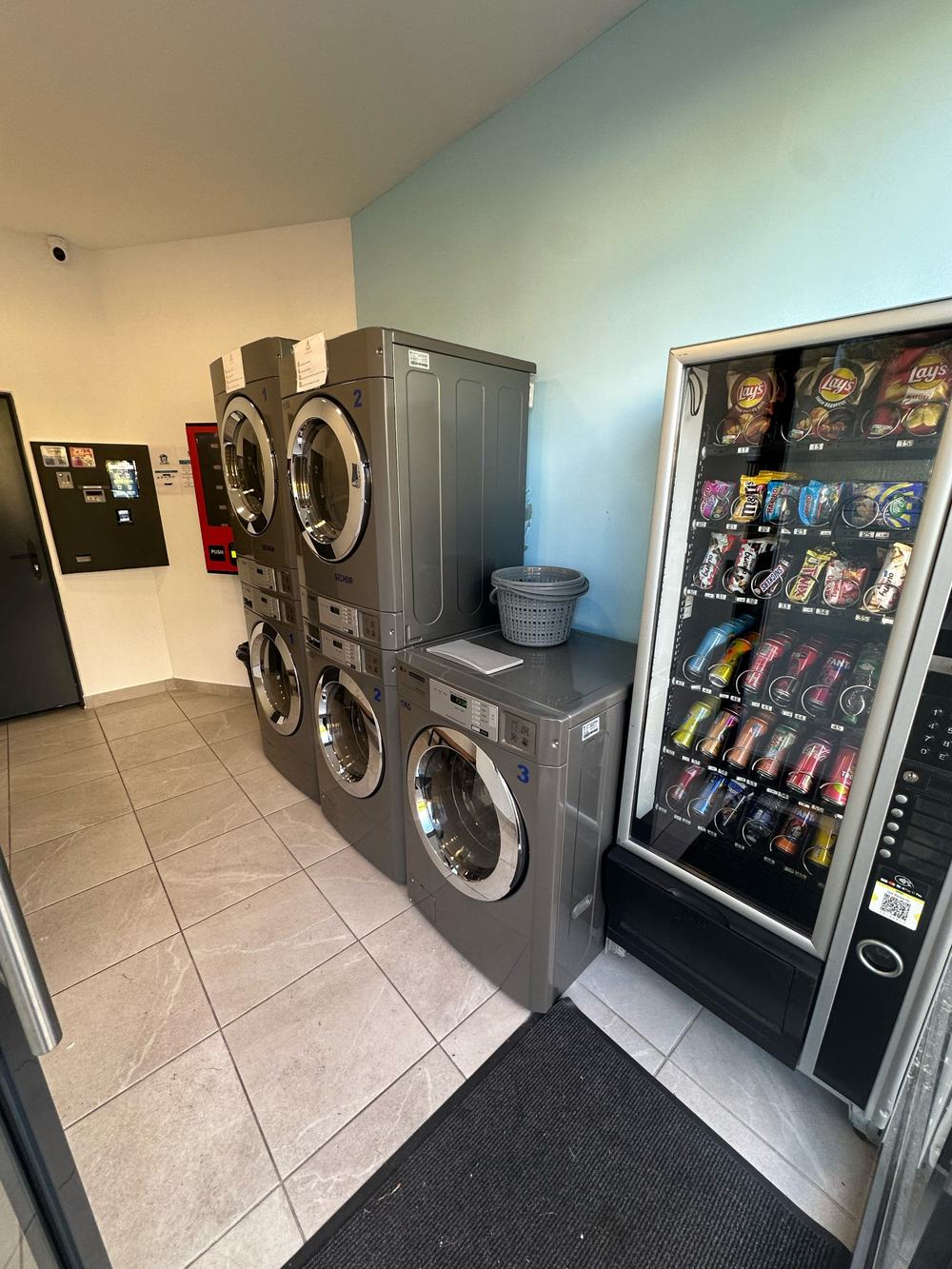 Intérieur de la laverie avec les machines, la centrale de paiement et le distributeur de snacks